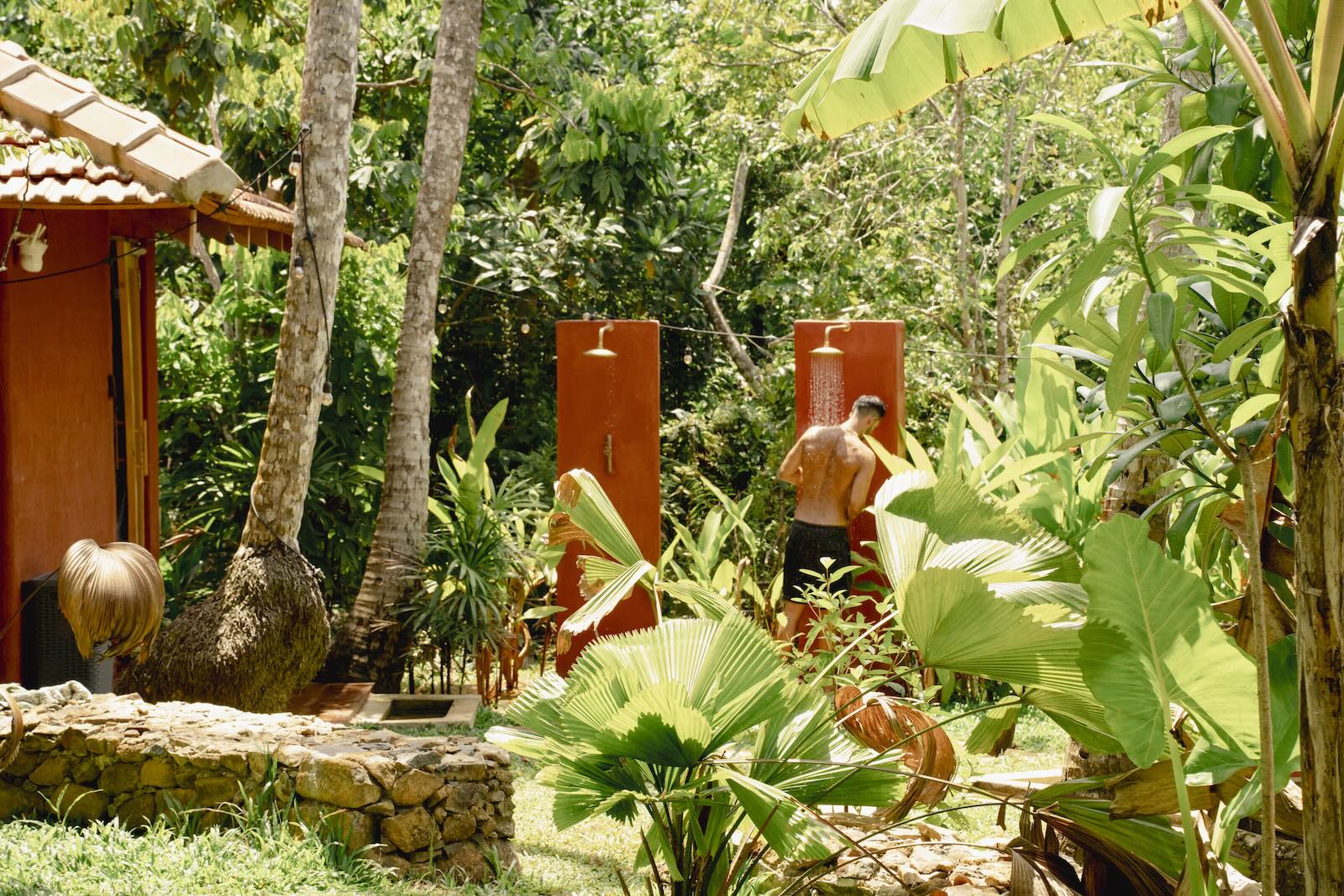 Outdoor showers tucked into the jungle garden, someone rinsing off under the trees